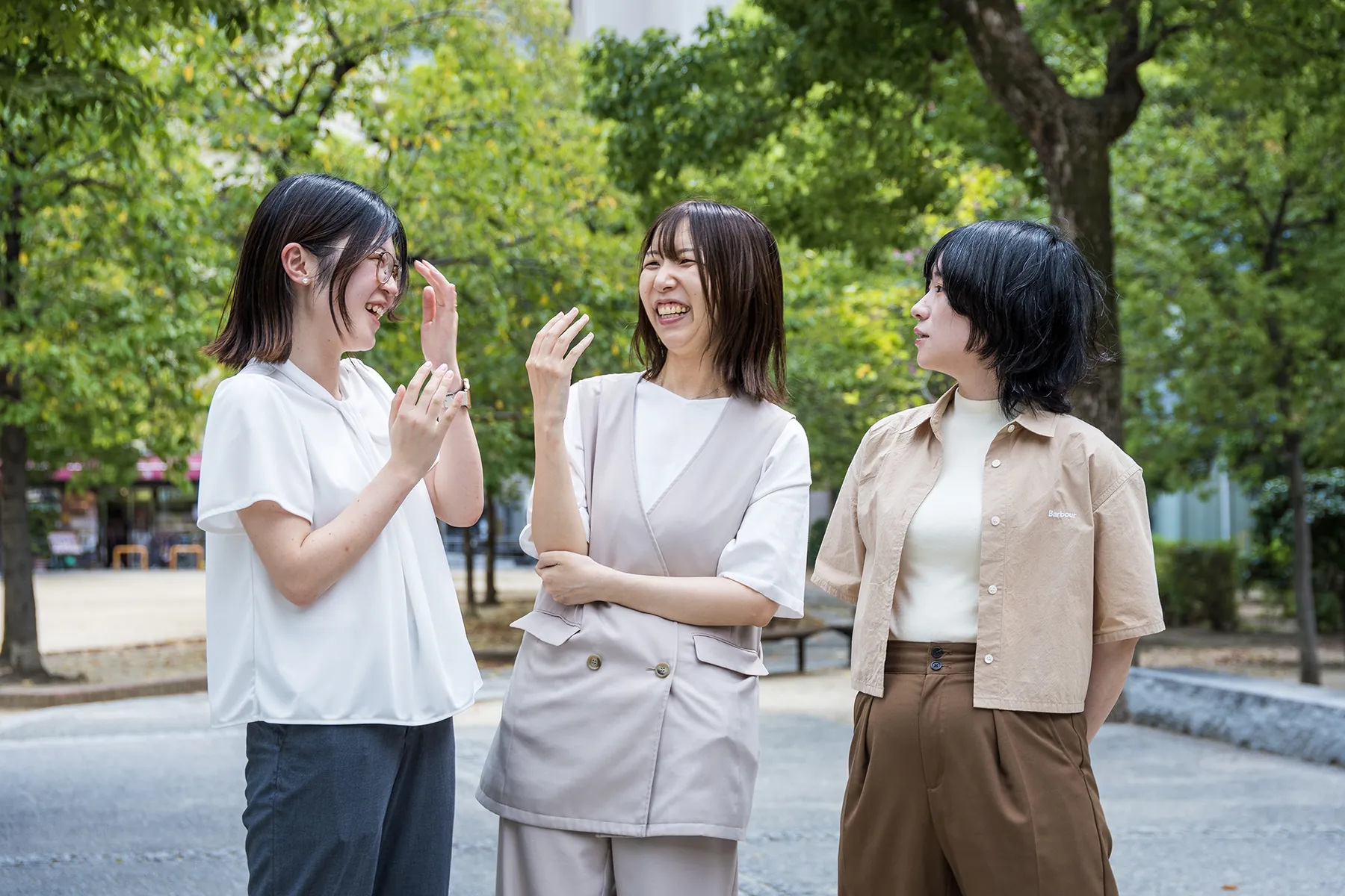 屋外で身振りを交えながら笑って話し合うesprotのメンバー3名